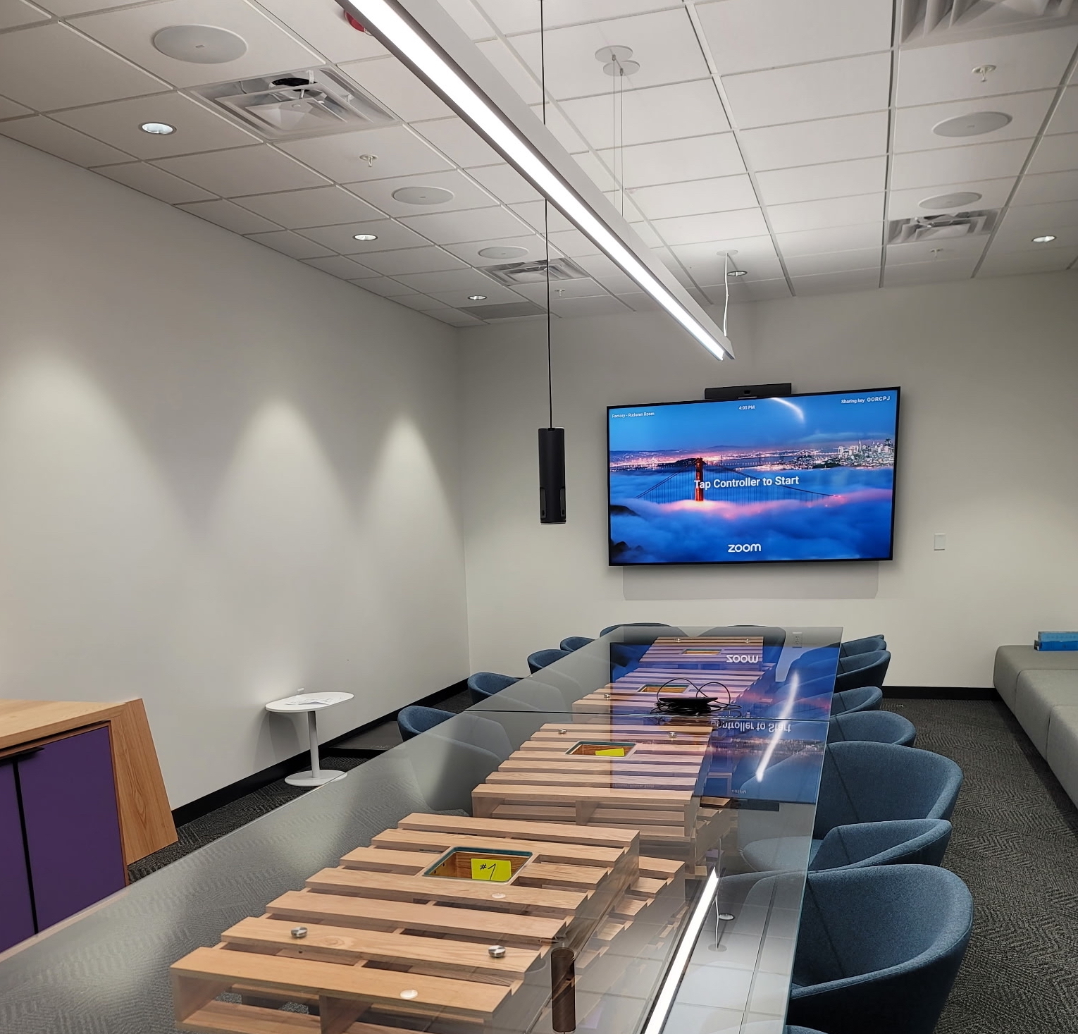 A rectangular conference room table with a wall-mounted TV at the far end.