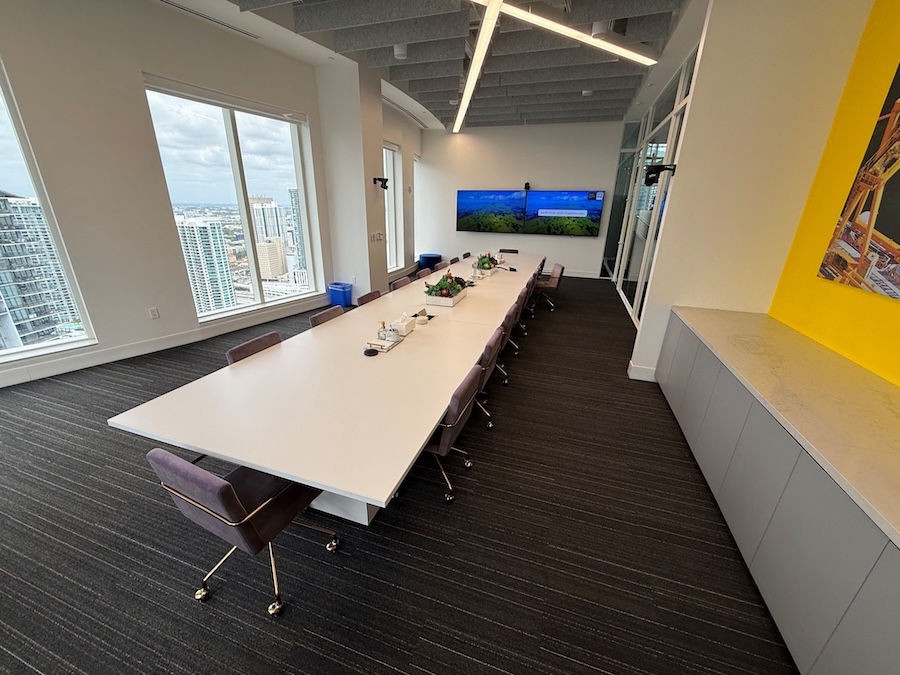 wall-mounted side-by-side display screens at the front of a boardroom with a camera mounted above them
